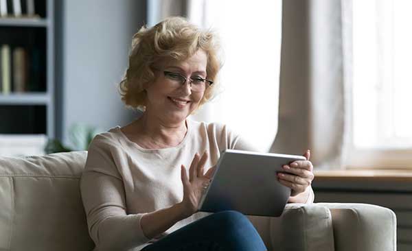 A woman looking at her Ipad and smiling.
